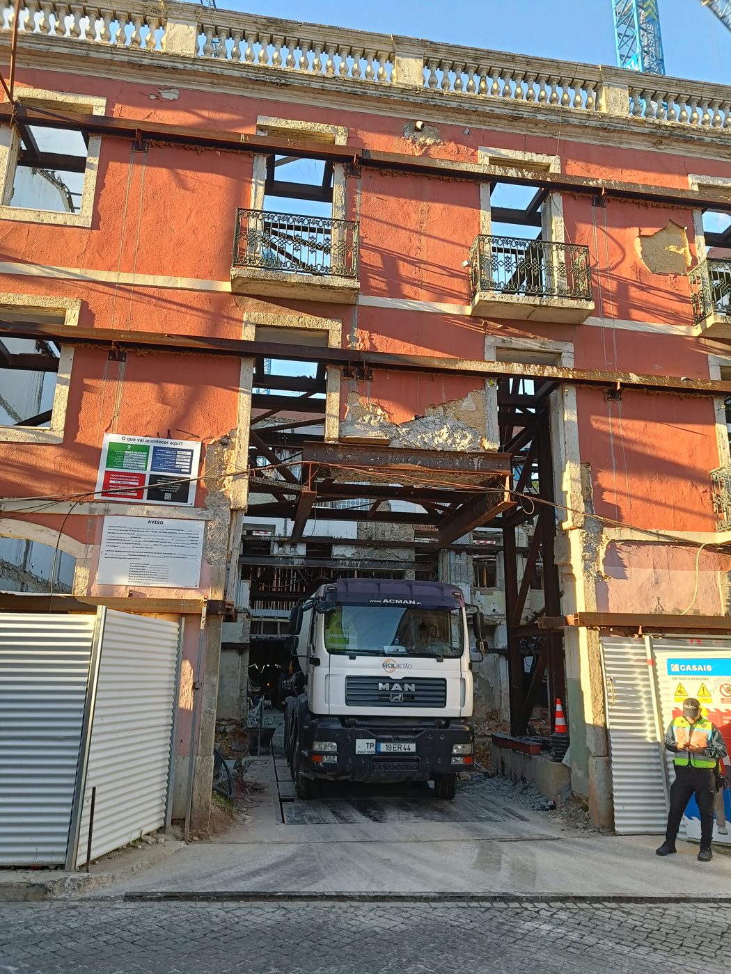A salmon-pink building front under renovation, with a construction truck parked in the opening at street level