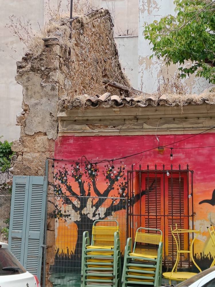A crumbling house with a painted red wall and shuttered windows