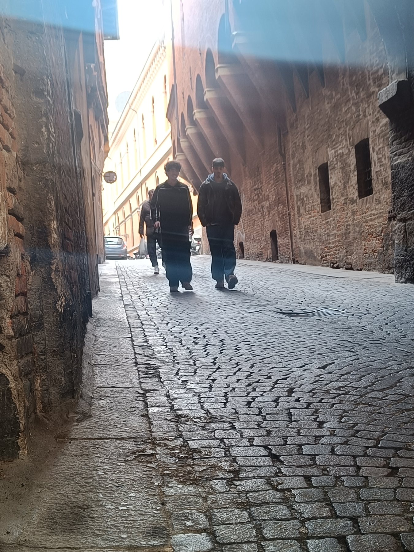 Two people walking up a narrow cobbled street between brick walls