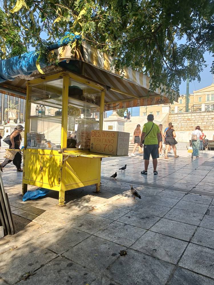 A yellow street kiosk on a sunny square