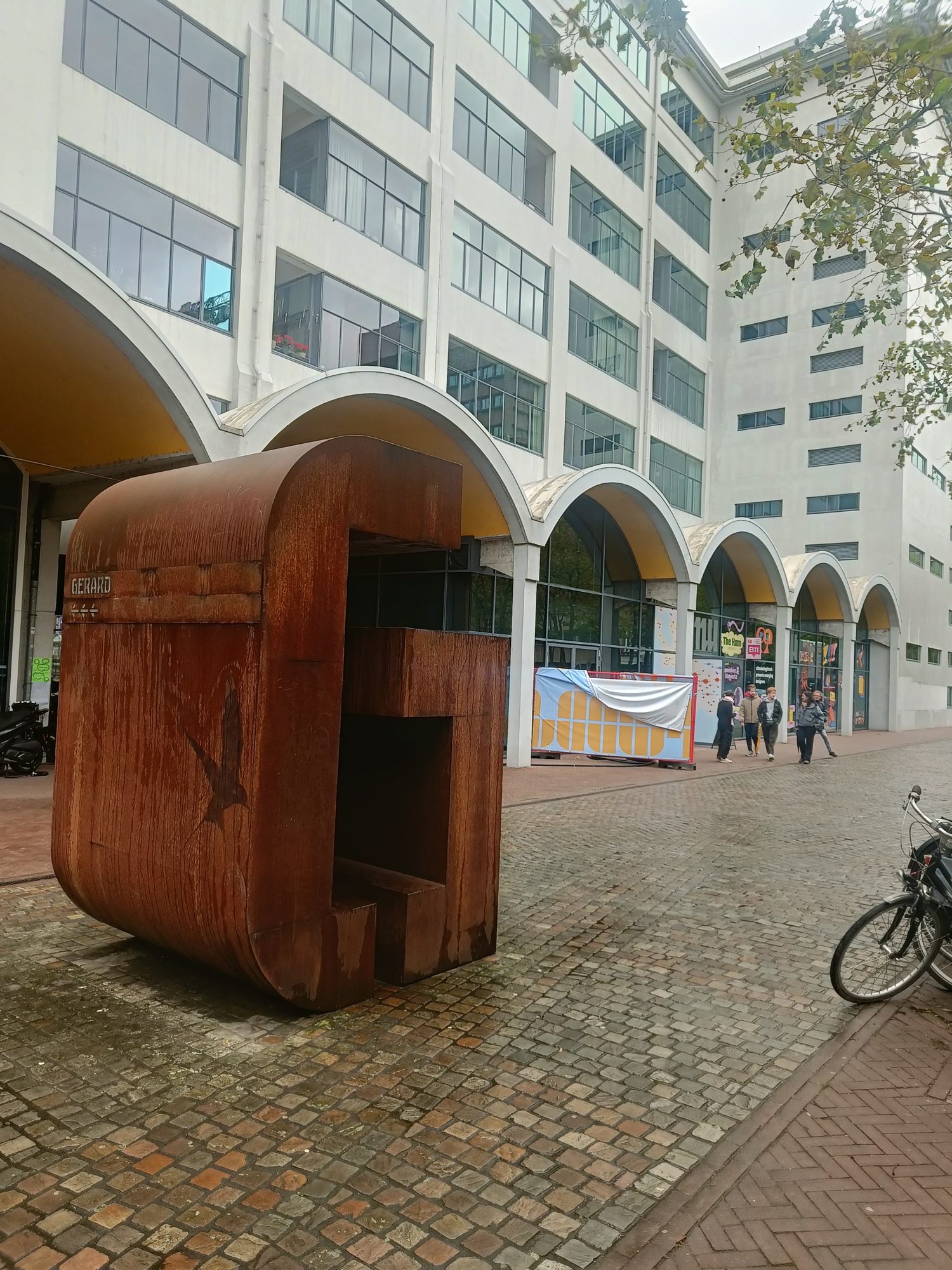 Visitors walking past the arched front of a former Philips building at Strijp-S during Dutch Design Week