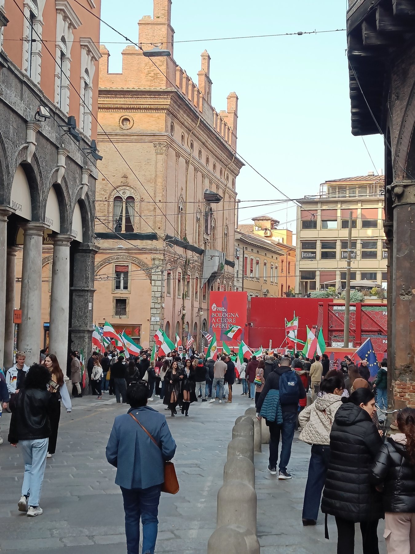 A march with Italian flags filling a street beside the porticoes